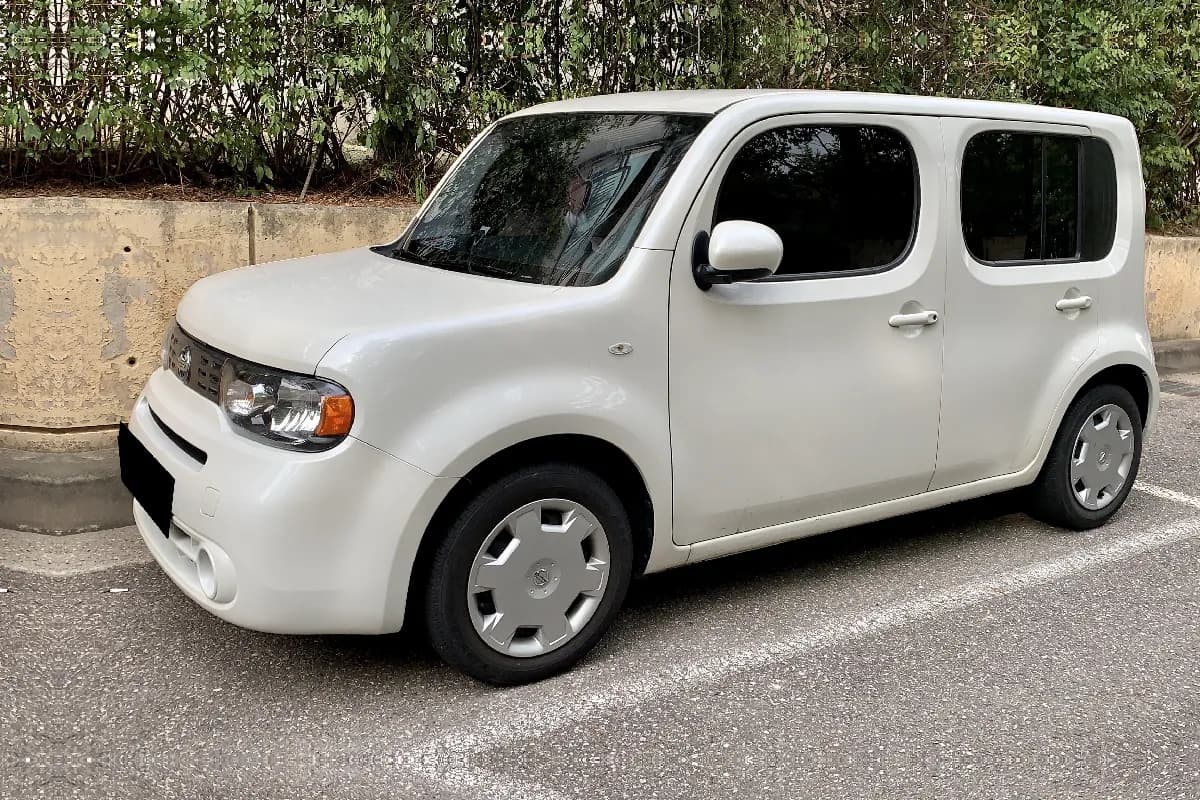 A white Nissan Cube hatchback, front three-quarter view
